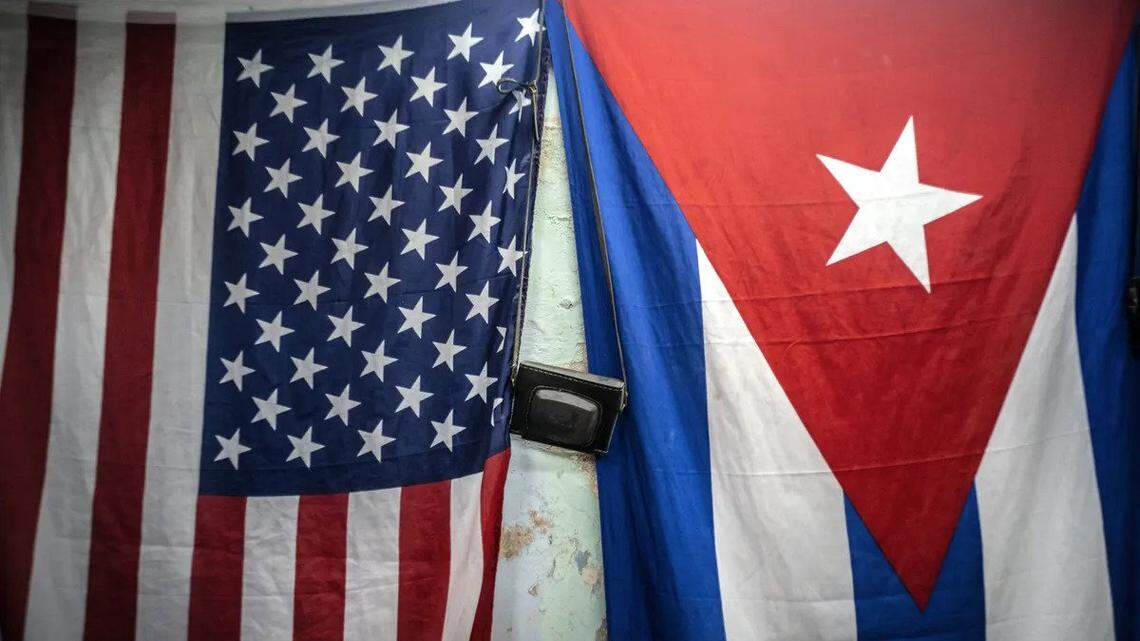 American and Cuban flags hang from a wall, with an old camera hung in between, in Havana, Cuba.