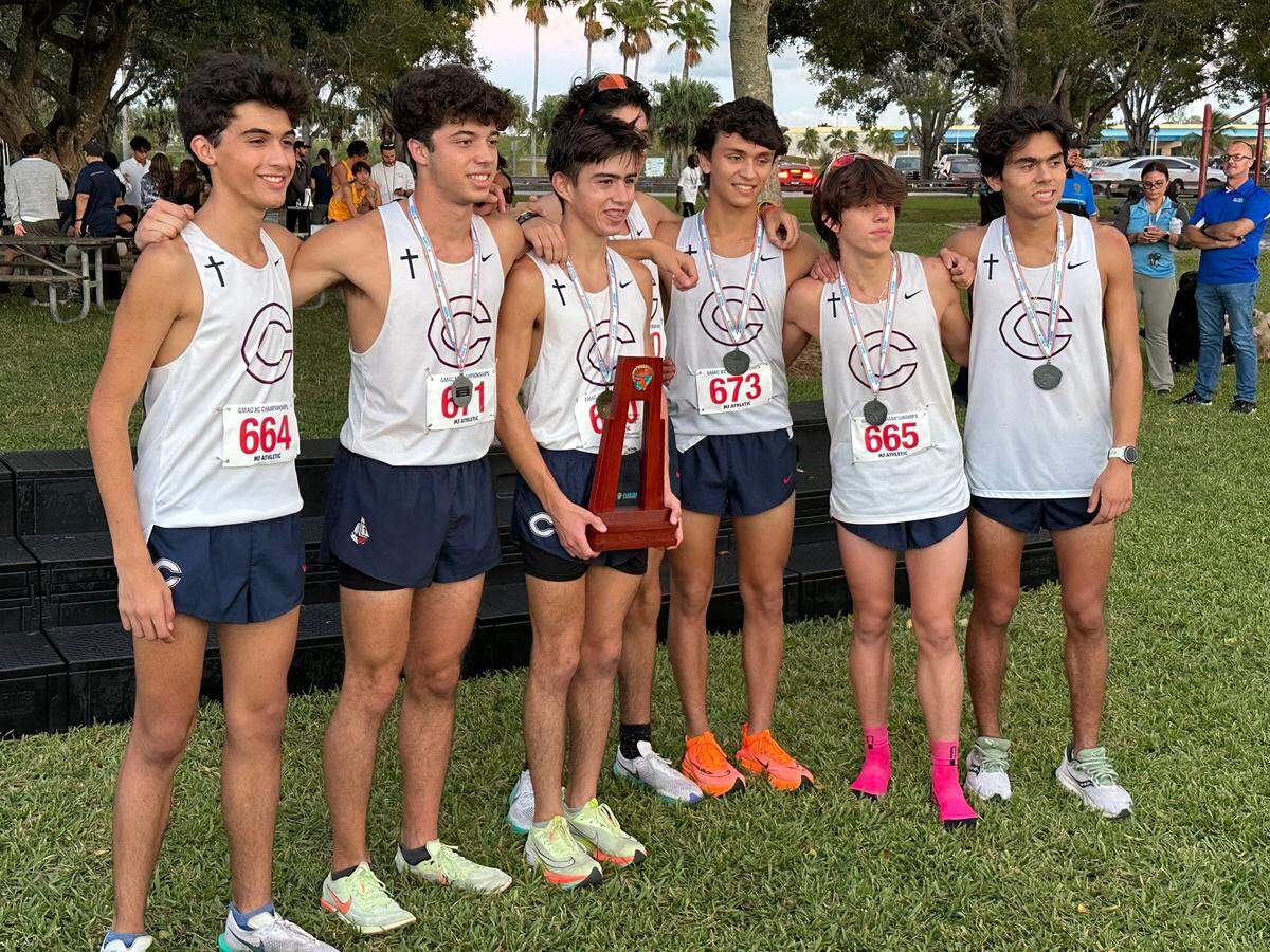 The Columbus cross-country team celebrates the Region 4-4A championship on Wednesday at Tropical Park. Individual champion Alejandro Romagosa (middle) holds the trophy.