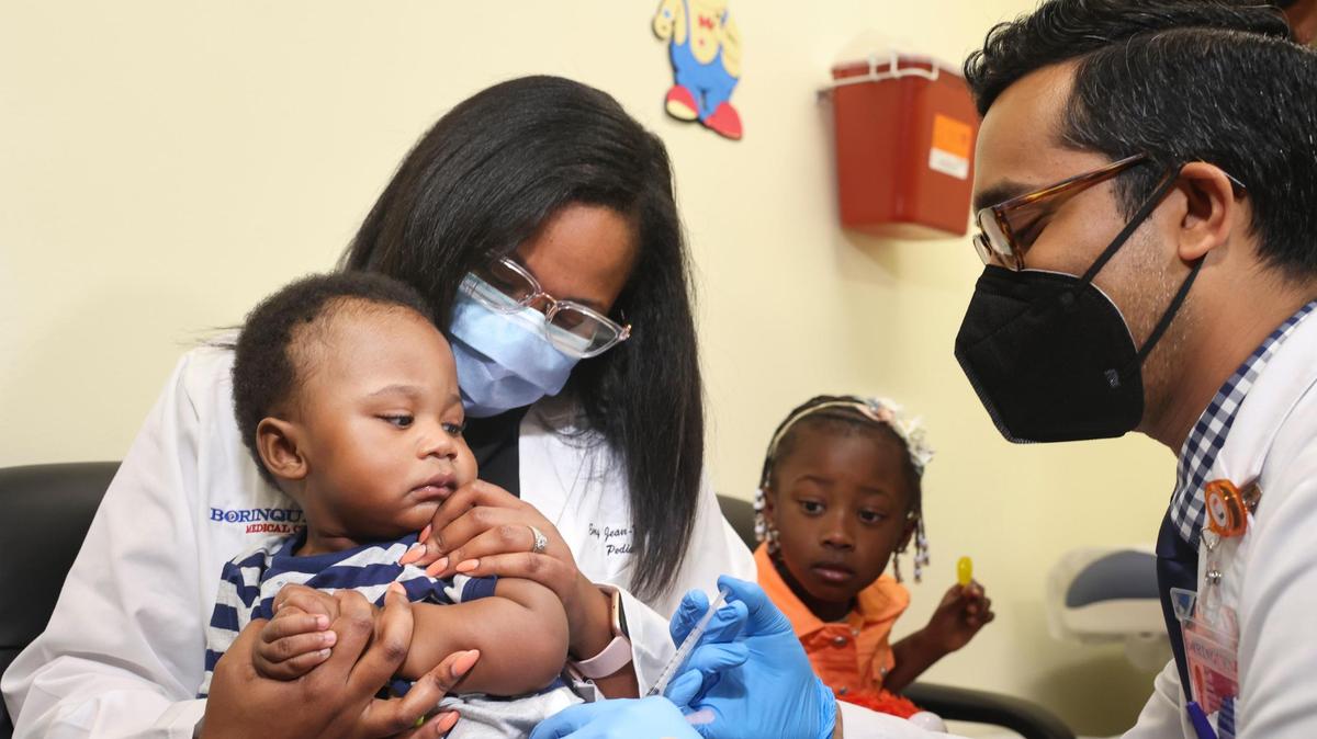 Dr. Nizar Dowla, right, gives a COVID-19 vaccine to 9-month-old Deji Adebayo while his mother, Dr. Emy Jean-Marie, and his sister, Emiola Adebayo, watch during a drive for children younger than 5 years old on Tuesday, June 28, 2022, at Borinquen Health Care Center in Miami. Assistant Secretary for Health Admiral Rachel Levine and Miami-Dade Mayor Daniella Levine Cava both attended the drive.