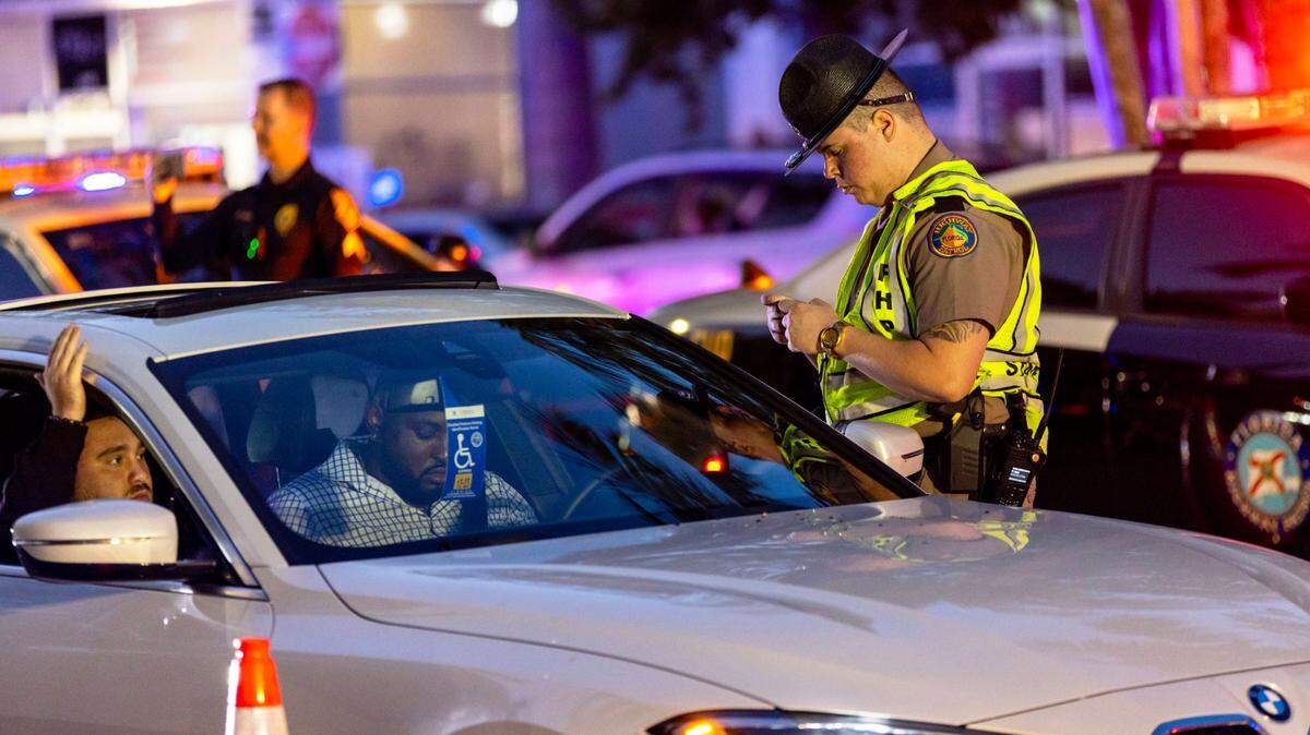 A Florida Highway Patrol officer interacts with a driver at a DUI checkpoint on Fifth Street between Meridian and Washington avenues in Miami Beach on March 25, 2023.