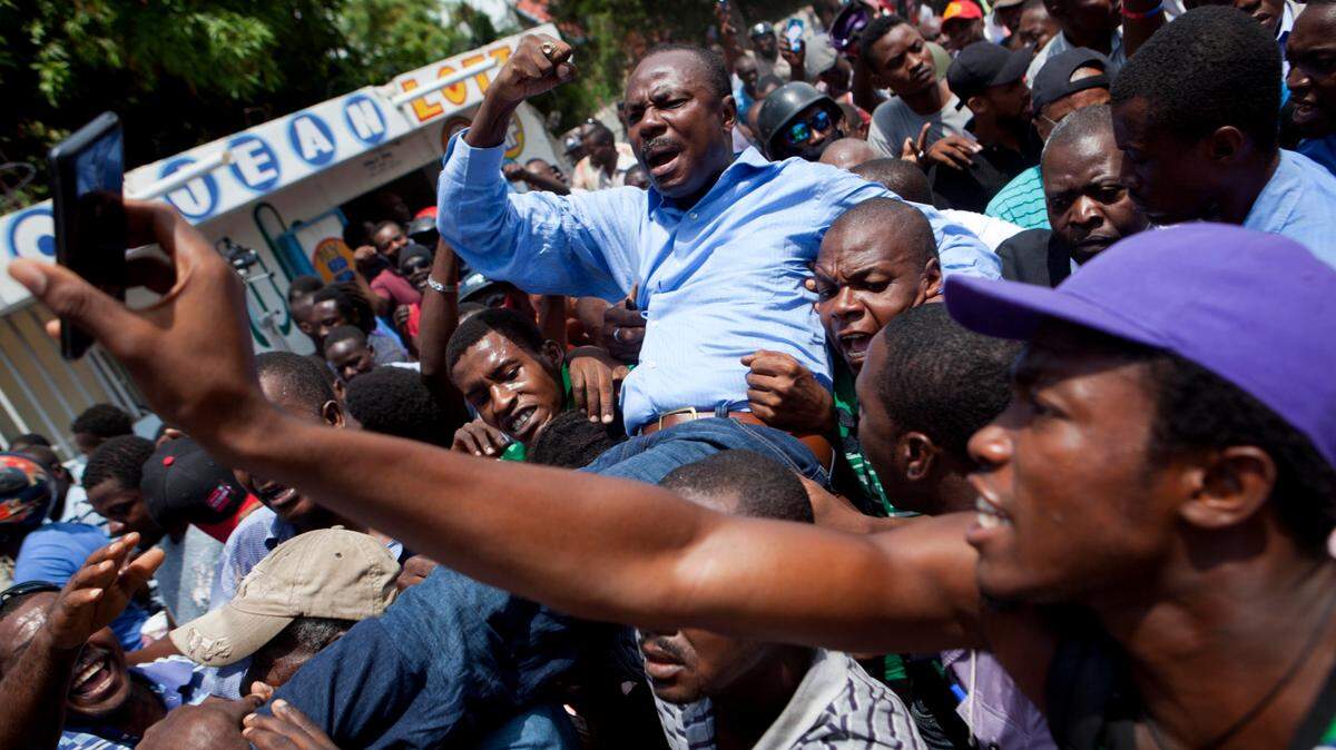 Former presidential candidate Moise Jean-Charles, from the Platform Pitit Dessalines party, is carried by supporters after national police officers attempted to detain him in Delmas, a district of Port-au-Prince, Haiti, Wednesday, Sept. 13, 2017. Moise’s attempted detention happened after the government claimed he had organized a violent protest in the capital on Tuesday, against government tax hikes that will take effect by October. (AP Photo/Dieu Nalio Chery)