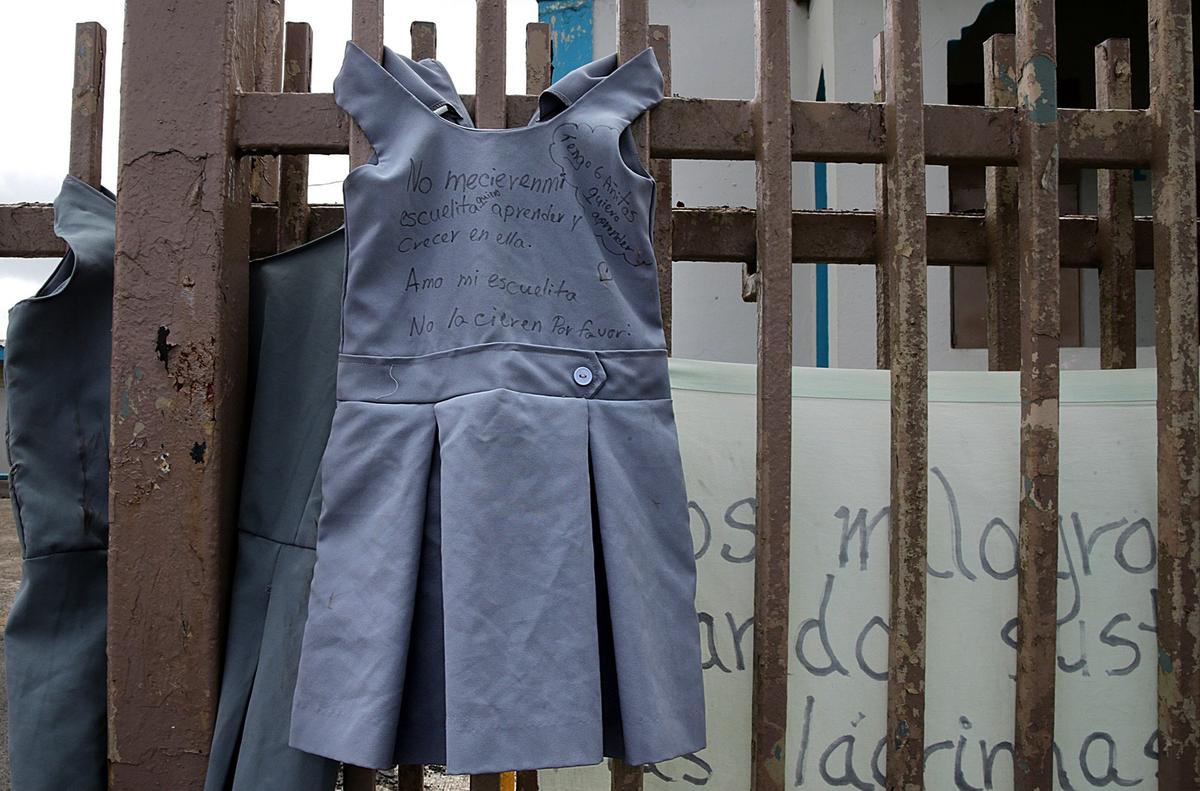 School uniforms hang on a fence outside Marcos Sánchez K-8 Center with messages on them asking Puerto Rico Education Secretary Julia Keleher to reopen the school.