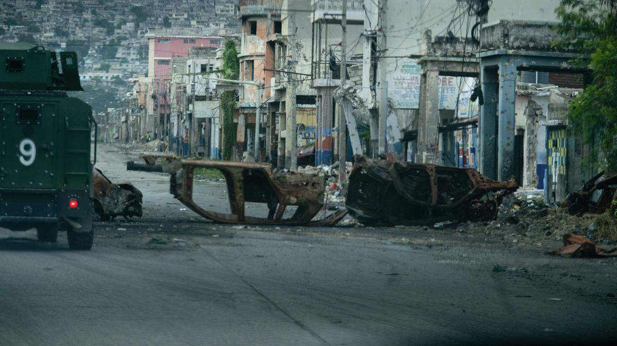 A police vehicle drives around cars burned by armed gangs and used as a barricade during clashes with Haitian security forces on a deserted street in the city center, seen from an armored police vehicle during a patrol, in Port-au-Prince on January 16, 2026. 
