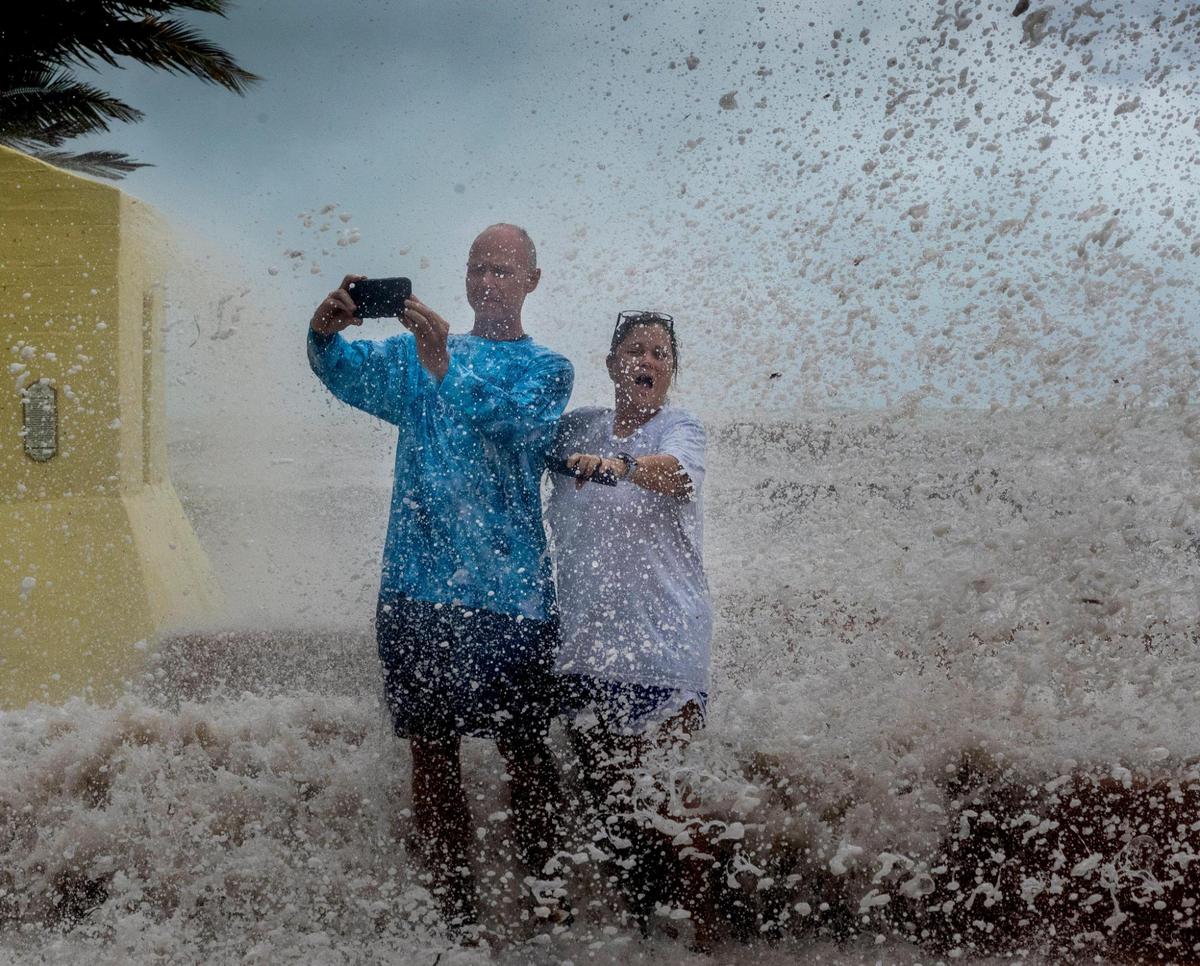 Gene and Laura Smith from Titus, Ala., get doused by waves as they pose for a video at the Southernmost Point in Key West on Tuesday, Sept. 27. Gene and Laura are on vacation and they stopped by the Southernmost Point to experience some of the effects of Hurricane Ian.