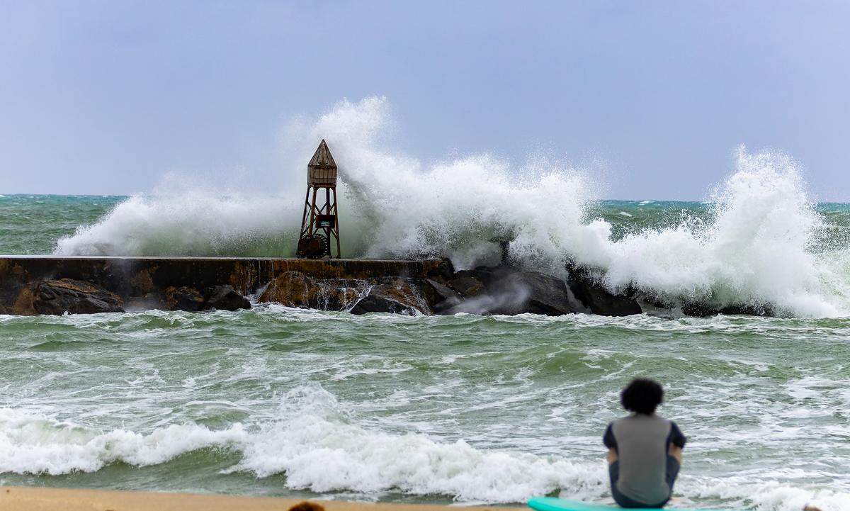 A surfer watches waves crash against the jetty at the Bal Harbour Lighthouse on Tuesday, Nov. 5, 2024, in Bal Harbour, Fla. Rip current risk remains in effect through Thursday evening according to the National Weather Service in Miami.
