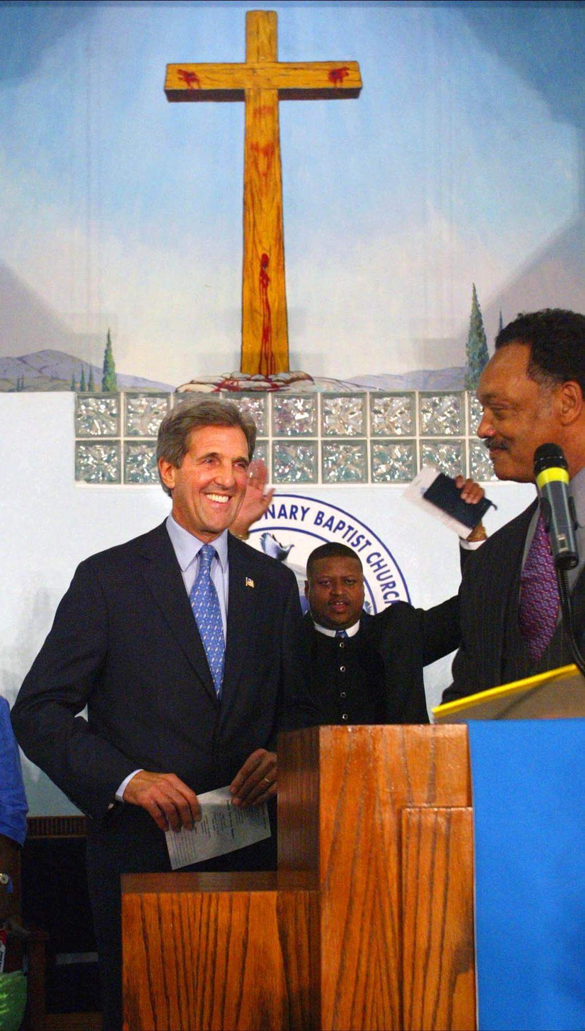 In 2004, Sen. John Kerry takes to the pulpit as he prepares to address the congregation. Rev. Jesse Jackson smiles after introducing the presidential canidate at Friendship Missionary Baptist Church in Miami. Pastor Gaston E. Smith is at center.