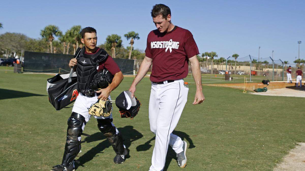 From left, Miami Marlins catcher Chris Hoo talking with pitcher Brian Ellington as they wearing Marjory Stoneman Douglas hats and T-shirts before the start of a spring training baseball game at Roger Dean Chevrolet Stadium on Friday, February 23, 2018 in Jupiter. Marlins honoring Stoneman Douglas shooting victims with special hats, T-shirts, patches.