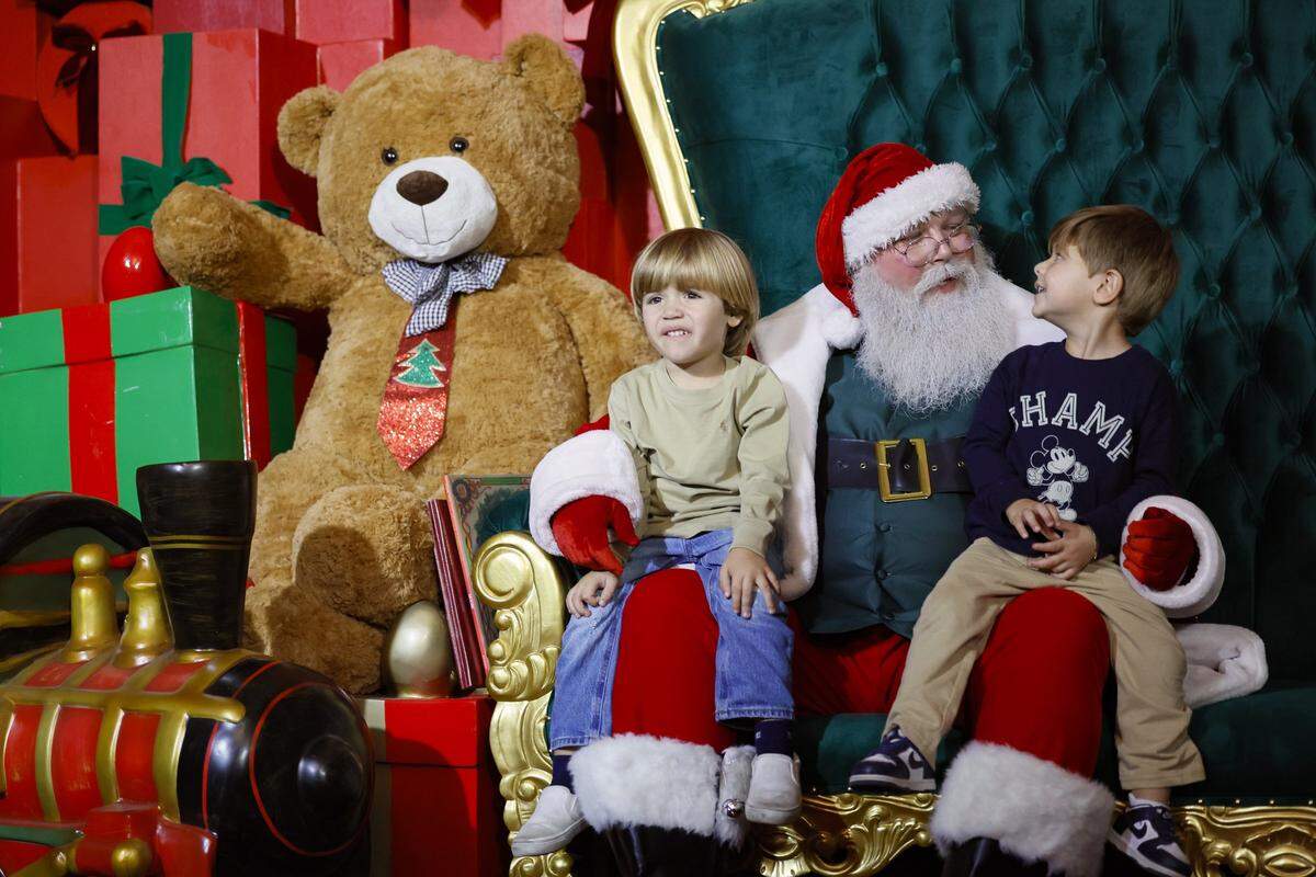 Santa Claus sits with Aiden Garcia, 4, at left, and Michael Jimenez, 3, at right, while visiting Christmas Wonderland at Tropical Park, a Miami-style holiday celebration of flavor and culture in Miami, Florida on Thursday, November 13, 2025.