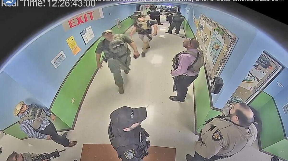 Law-enforcement officers from several agencies crowd into the hallway of an elementary school while a mass shooter remains in the building.