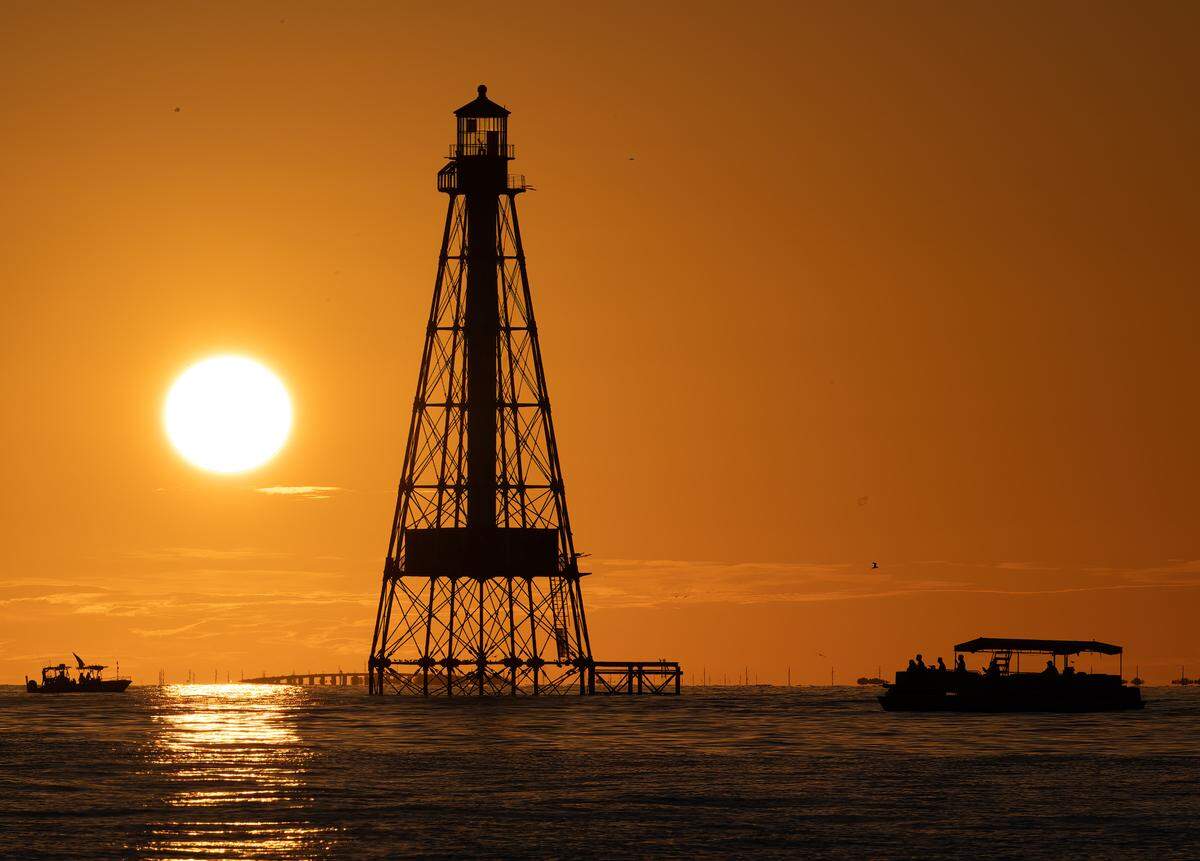 Los navegantes observan una puesta de sol detrás del Faro Alligator Reef, el viernes 6 de octubre de 2023, frente a Islamorada en los Cayos de la Florida.