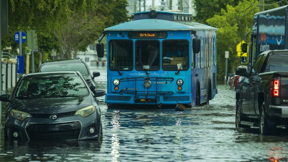 The North Beach trolley drives through Crespi Boulevard during king tide in Miami Beach Florida.