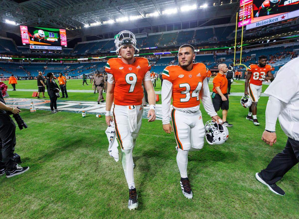 Miami Hurricanes quarterback Tyler Van Dyke (9) and Hurricanes linebacker Ryan Ragone (34) walk off the field after being defeated by North Carolina Tar Heels 27-24 during an ACC conference football game at Hard Rock Stadium on Saturday, October 8, 2022 in Miami Gardens, Florida..