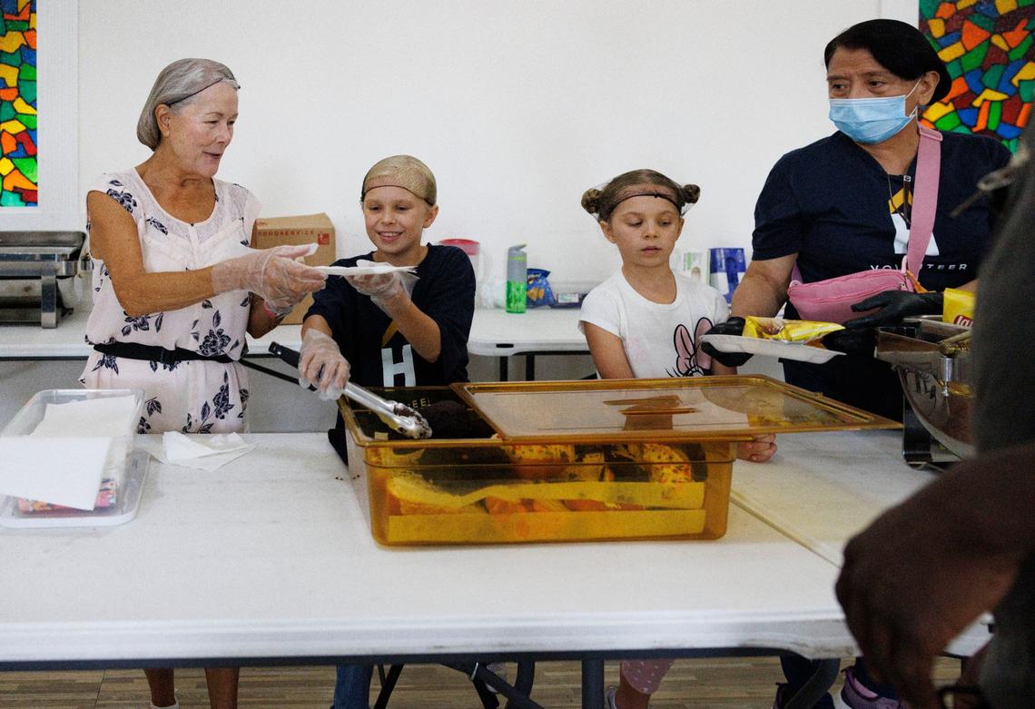 Charletta Strauss, left, and her granddaughters Camille Adams, 9, center, and Celine, 8, during lunch time on Thursday, Sept. 5, 2024, at HOPE South Florida in Fort Lauderdale. The girls take a break from homeschooling once a week to serve lunch to the community. “People come in here and they say they feel so peaceful; they feel safe,” said volunteer Verel Johnson.