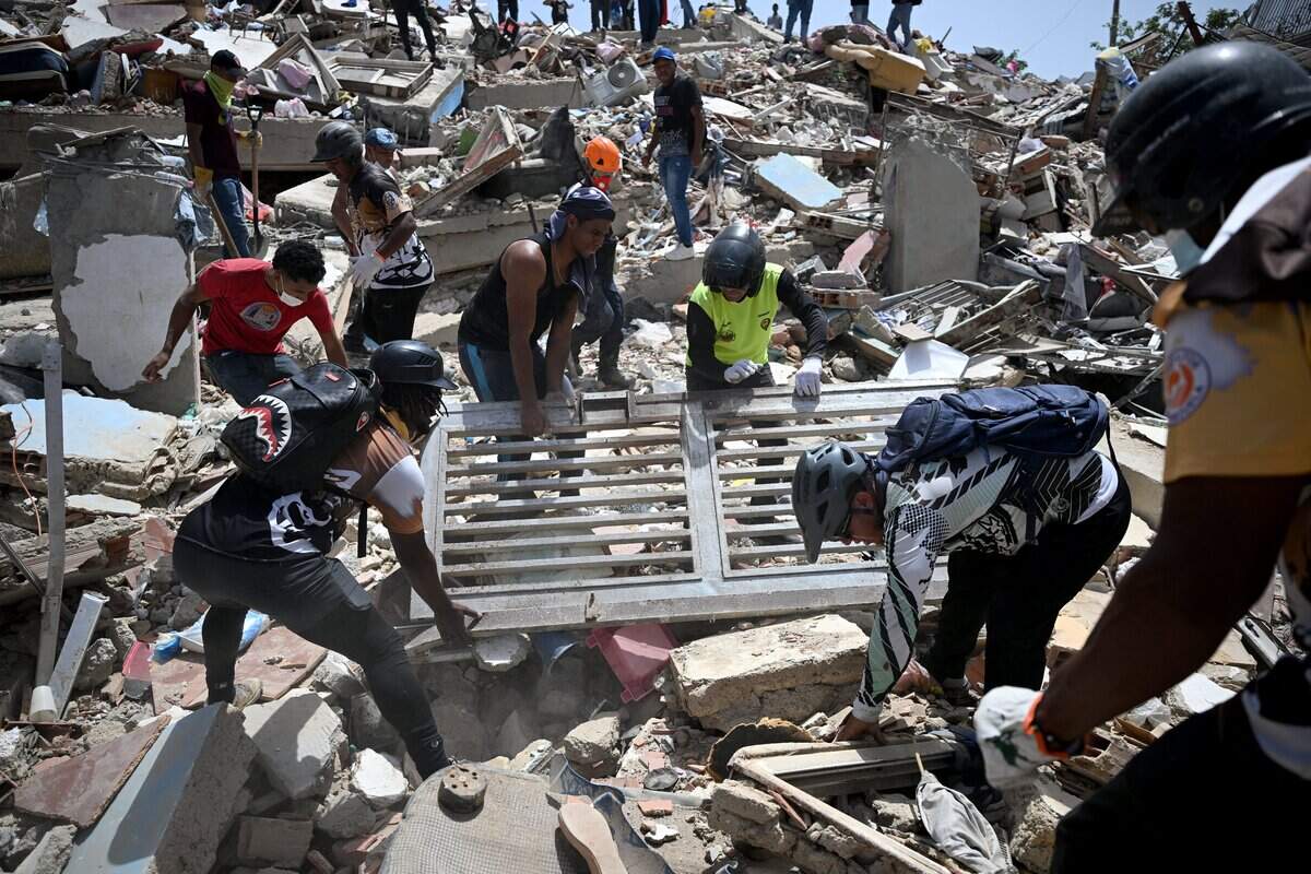 Volunteers lift a metal gate as they search for survivors in Catia La Mar, La Guaira state, Venezuela, on June 26, 2026.