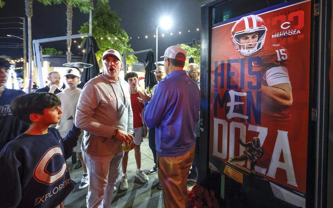 Massimo Andreu, 8, at left, views a poster of Christopher Columbus High School alumnus and Indiana Hoosiers quarterback Fernando Mendoza as friends and family gather at a watch party at Vice Pizza in South Miami, Florida. Mendoza is later announced as the winner of the Heisman Trophy on Saturday, December 13, 2025. 