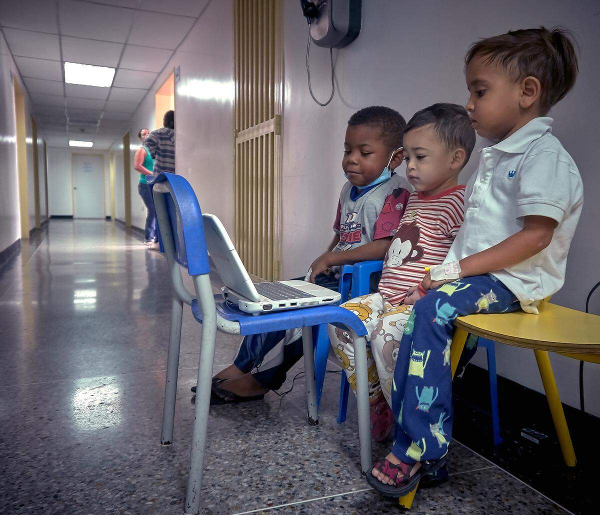Ramsses Millan, 5, (in the foreground) is watching their favorite cartoon with two friends while seated in the corridor at the nephrology department at a hospital in Caracas, Venezuela.