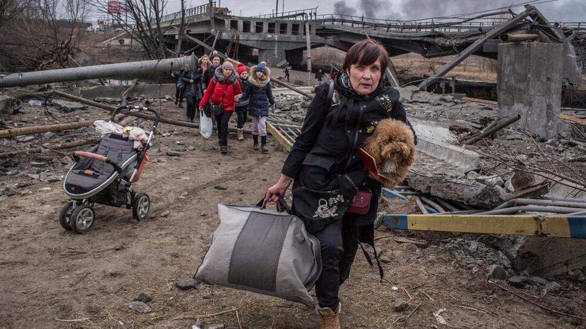 People cross an improvised path under a destroyed bridge as they flee the town of Irpin, Ukraine. The conflict in Ukraine has had rippling effects on gas prices and inflation in Kentucky.