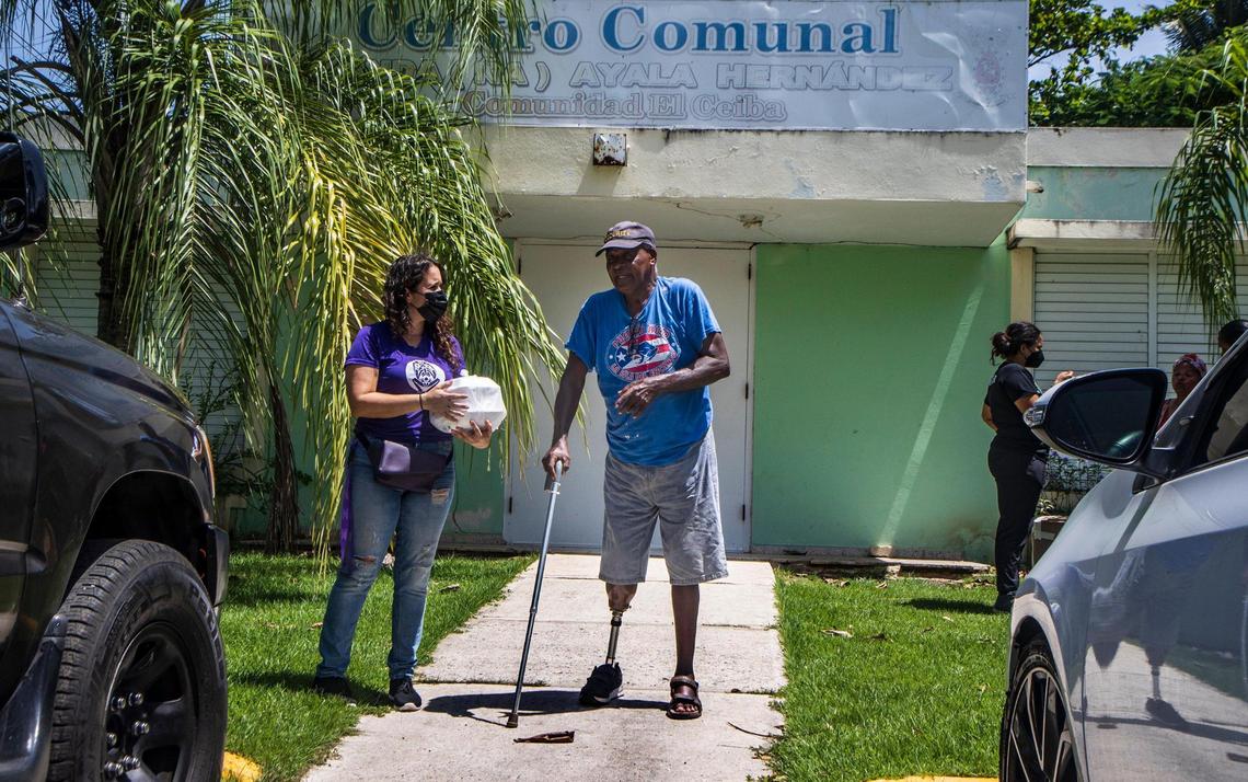 Jenifer de Jesus, director of Taller Salud, assists resident Mario Carrasquillo Lopez, who came to get lunch at the soup kitchen created by the non profit group in Loíza, that mobilize to respond to Fiona in the town of Loíza on the northeastern coast of Puerto Rico as the hurricane passed by the island on Monday September 18, on Wednesday, September 21, 2022.