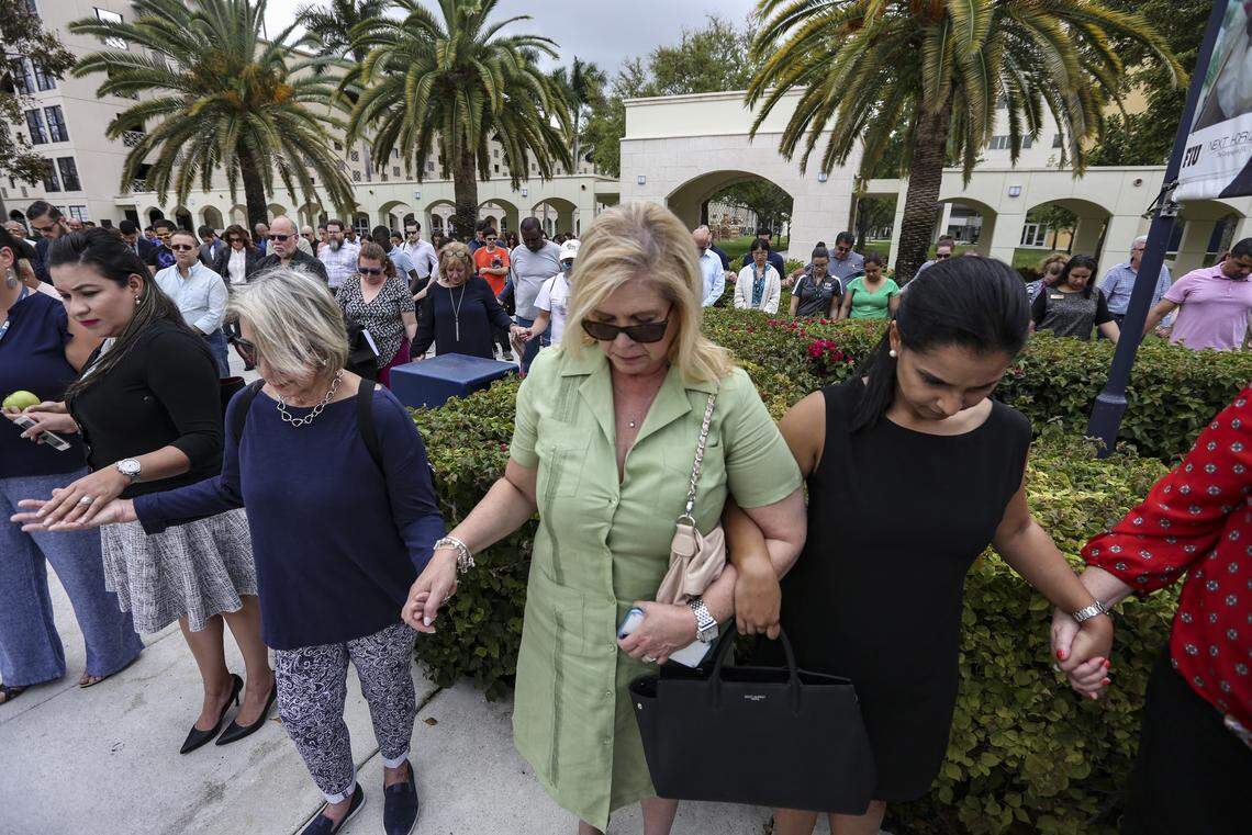 Virginia Esparza, Olga Hernandez and Indira Pardillo hold hands as FIU holds a moment of silence to commemorate the one-year anniversary of the bridge collapse on March 15, 2019. A new bridge will memorialize the victims of the collapse.