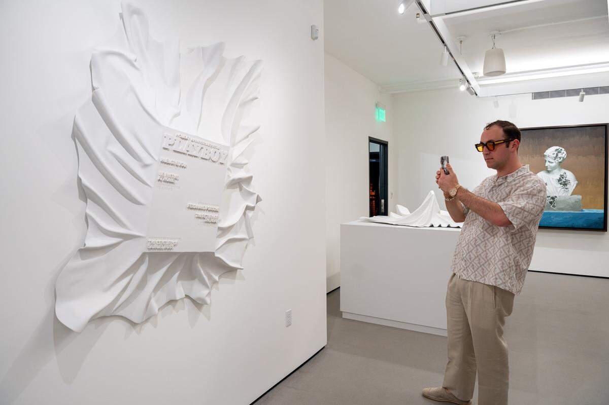 A visitor takes a photo of “Veiled Playboy Magazine” by artist Daniel Arsham at Ross+Kramer Gallery’s new Miami Beach location.