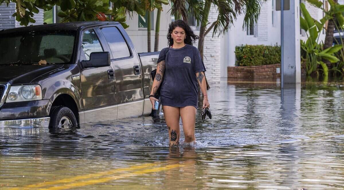 Claudia Stevens walks barefoot through the flooded streets of Miami Beach.