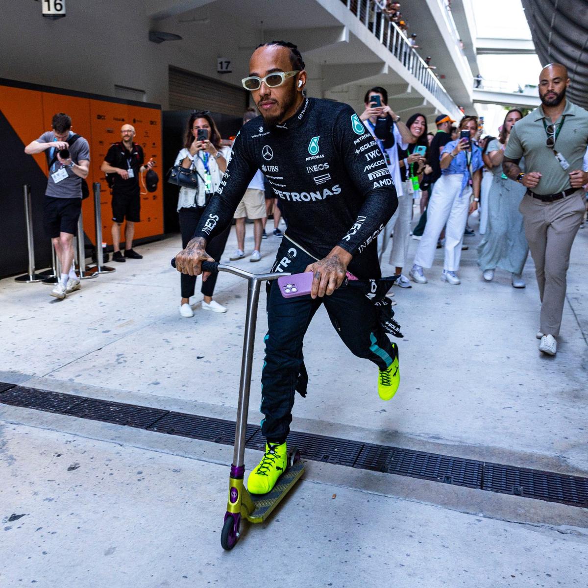 Mercedes driver Lewis Hamilton of Britain scooters through the paddock on his way to the Mercedes garage.