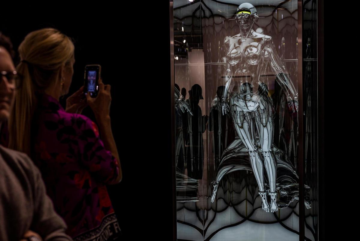 A woman takes a photo of Hajime Sorayana’s piece called “Untitled_Sexy Robot type II” during Art Basel VIP opening day at the Miami Beach Convention Center