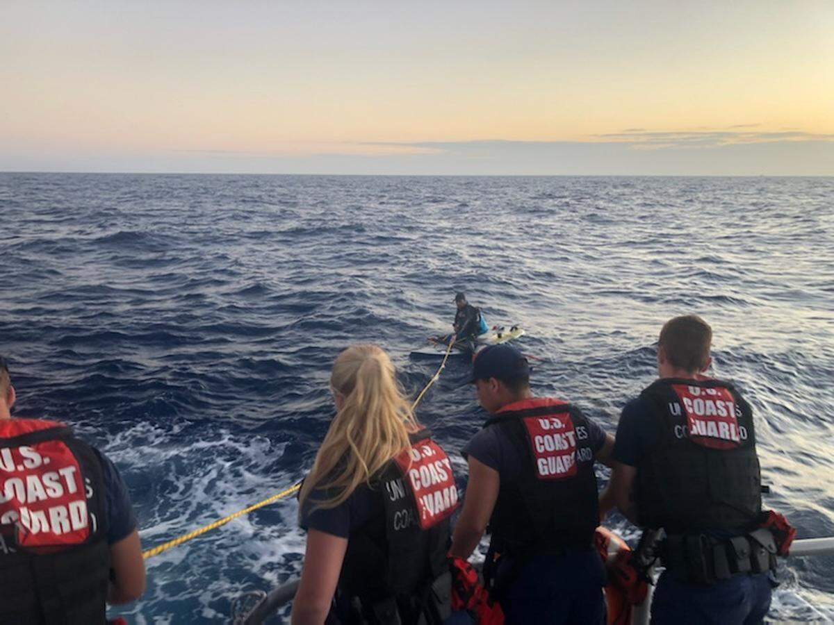 A U.S. Coast Guard crew approaches a man stranded on a windsurf board about 15 miles off the Florida Keys Wednesday, March 23, 2022.