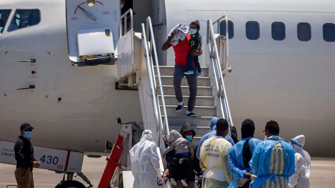 In May 2020, healthcare workers watch as Haitians who were deported from the United States deplane in Port-au-Prince. President Biden has continued President Trump’s policy.