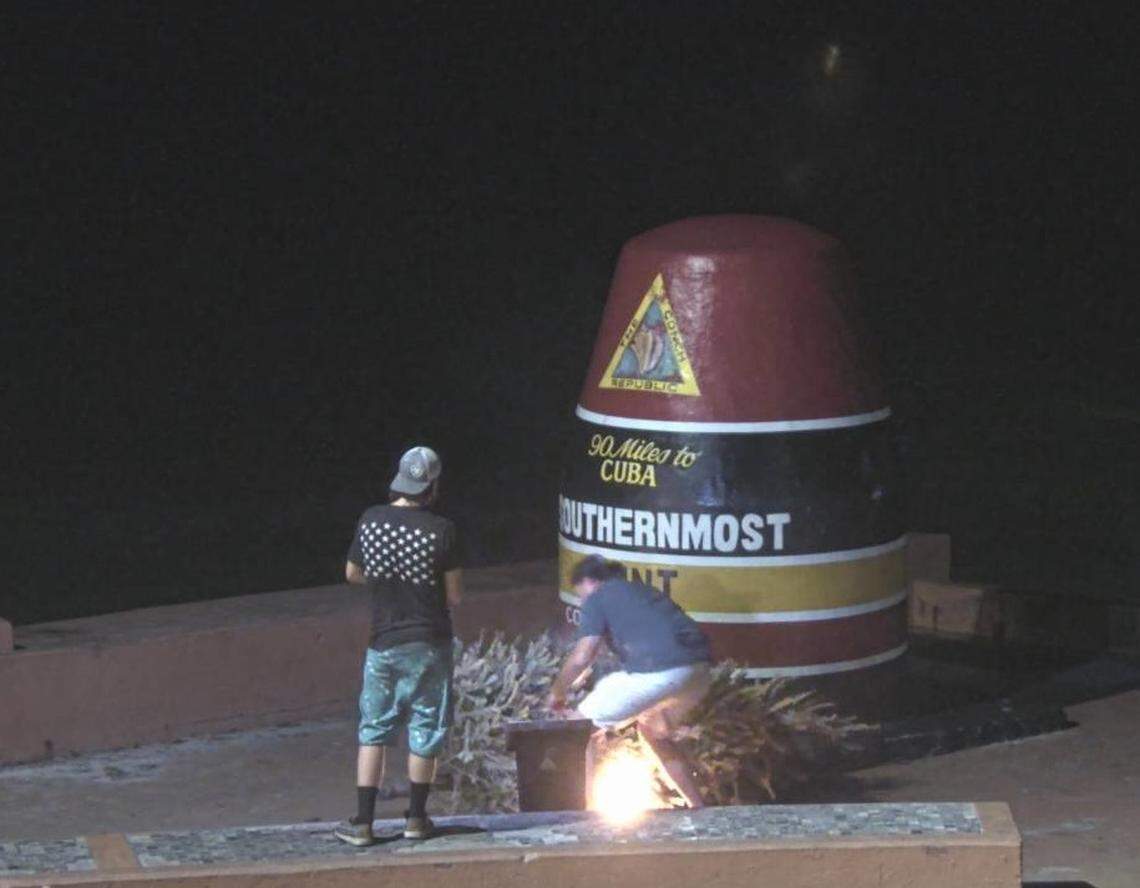 In a screenshot from a webcam, two people are seen setting a Christmas tree on fire beside the Southernmost Point buoy in Key West on Jan. 1, 2022.