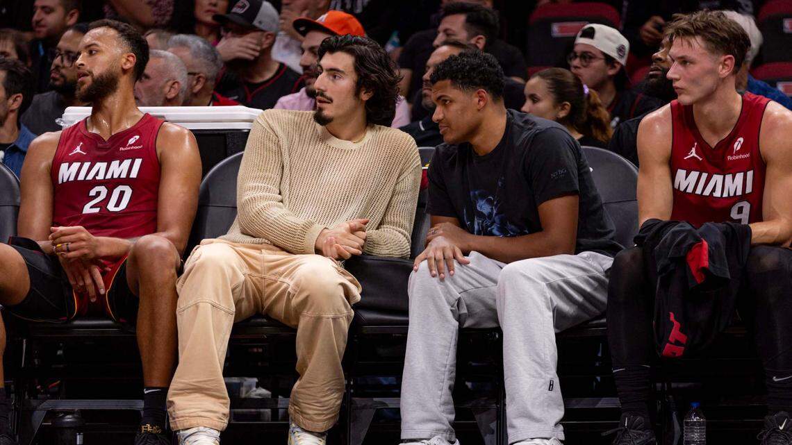 Miami Heat guard Jaime Jaquez Jr. speaks with teammate Dru Smith while the injured pair sit on the bench during the second half of an NBA game against the Washington Wizards at Kaseya Center on March 3, 2025, in Miami.