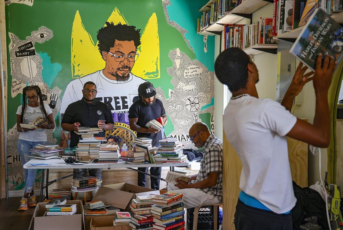 Sherina Jones, Isaiah Thomas, Phillip Agnew, Barney Agnew and Cameron Agnew (l. to r.) sort and place books on the shelves while preparing for the opening of Roots Bookstore and Marketplace, the brainchild of the late Danny Agnew. The shop is set to open on Juneteenth.