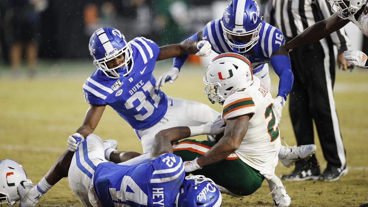Shaka Heyward (42) and Josh Blackwell (31) of Duke tackle Cam’Ron Harris (23) of the Miami Hurricanes at Wallace Wade Stadium on November 30, 2019 in Durham, North Carolina.
