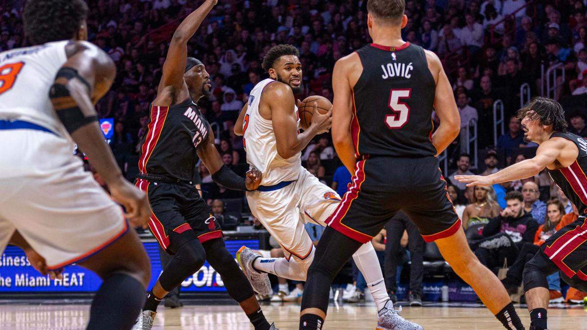 New York Knicks center Karl-Anthony Towns (32) drives into the paint while defended by Miami Heat center Bam Adebayo (13) during a game at Kaseya Center on October 30, 2024, in Miami.