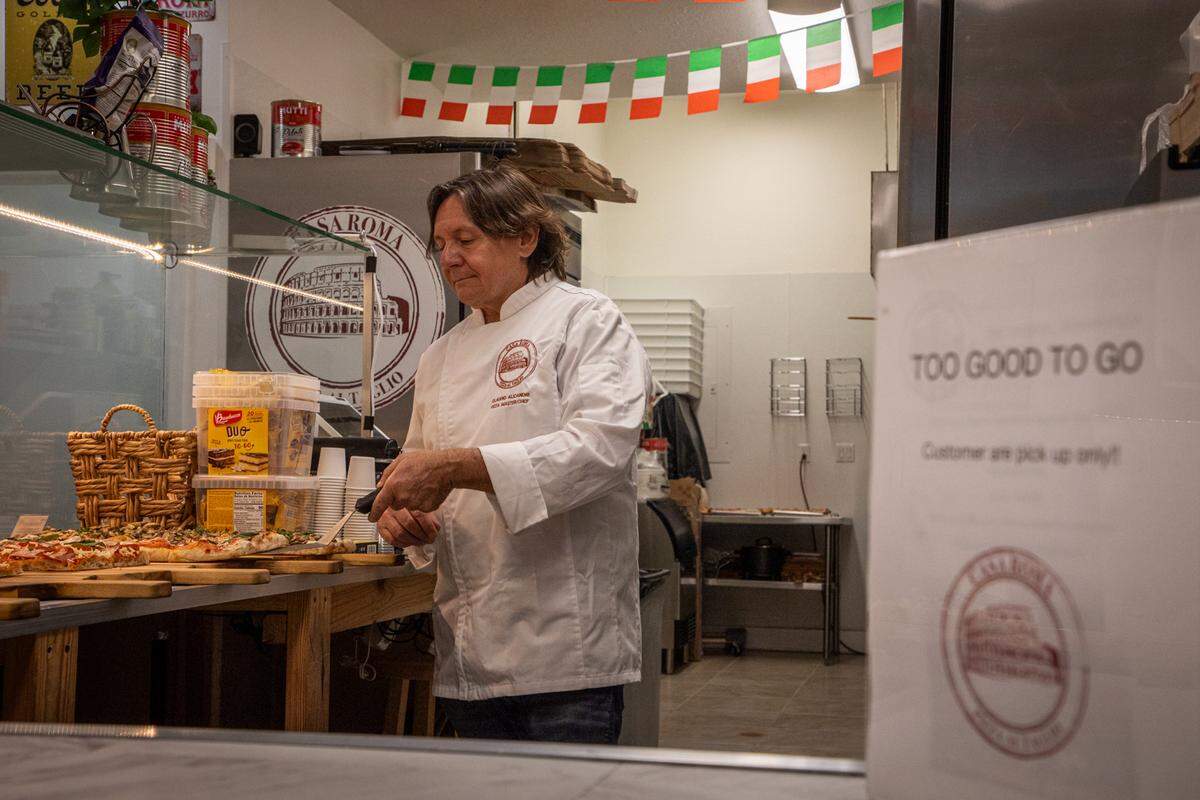 Claudio Alicandri picks pizza slices at random to put into a take-out box customers pick up through the app, Too Good to Go. Customers never know exactly what they will get when they pick up surplus food on restaurants on the app at a discounted rate.