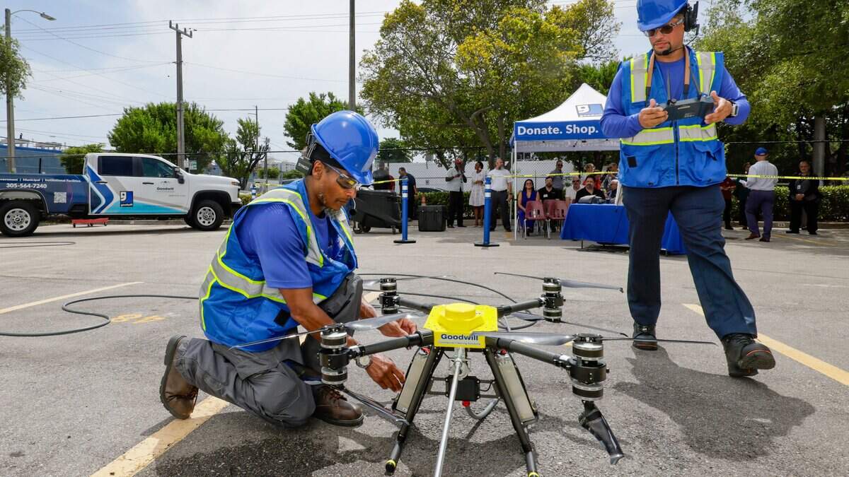 Airman Deandre Daniels checks on a drone as drone pilot Manuel Varela prepares for a demonstration at Goodwill’s drone demo day. Goodwill is launching a new drone-powered window cleaning service.