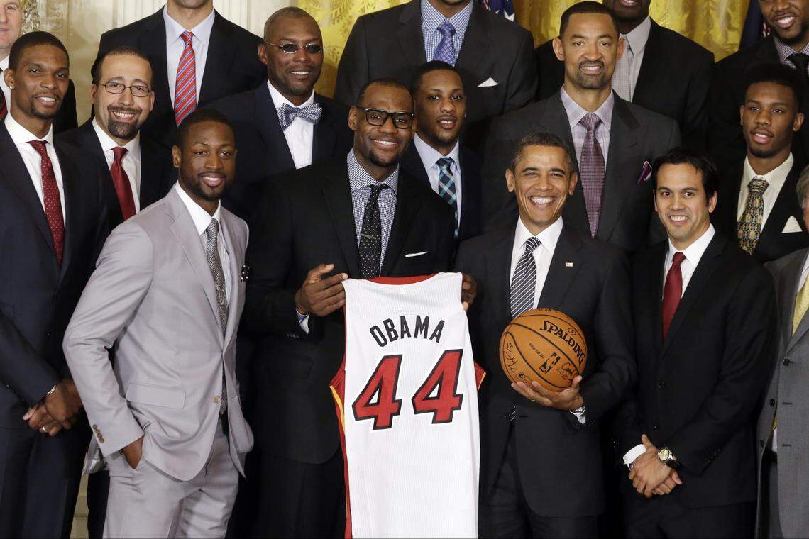 President Barack Obama stands with LeBron James, holding the jersey, Dwyane Wade, third from the left, and coach Erik Spoelstra, right, as he honors the NBA champions, the Miami Heat basketball team, in the East Room at the White House in Washington, Monday, Jan. 28, 2013.