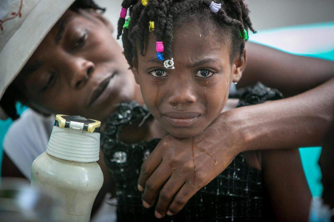 A young girl is comforted by her mother as nurses care for a wound on her foot at the hospital in Les Cayes on Monday.