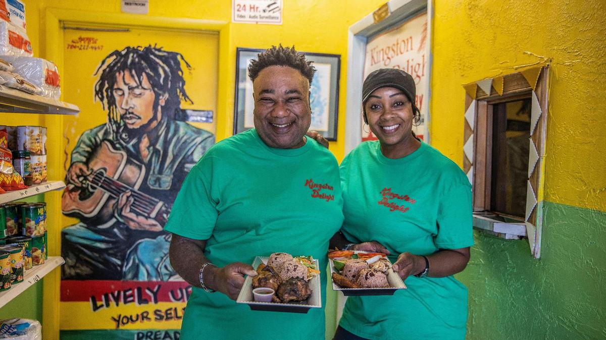 Donovan Thompson and his wife, Jeannette Thompson, owners of Kingston Delight, display Jerk Chicken and a Jamaican Escovitch Fish at their restaurant in North Miami Beach on Wednesday, March 9, 2022.