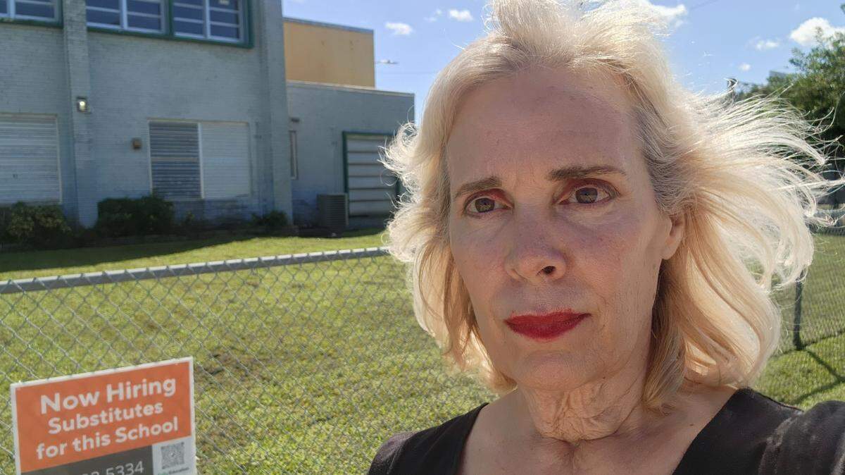 Marta Zayas, maestra de las Escuelas de Miami-Dade, posa junto a un cartel de Kelly Education en el exterior de la Primaria Biscayne Gardens. El distrito escolar firmó recientemente un contrato con Kelly Education para gestionar sus maestros sustitutos y redujo los requisitos. Ahora, cualquier persona que cumpla los requisitos de edad y tenga un diploma de secundaria tradicional o haya aprobado el examen GED puede solicitar ser maestro sustituto.