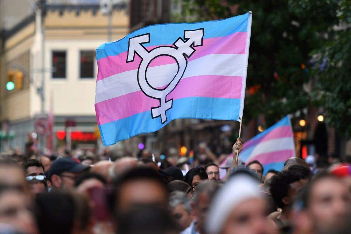 In 2019, a person holds a transgender-pride flag as people gather outside the Stonewall Inn in New York to mark the 50th anniversary of the Stonewall Riots, a turning point in the LGBTQ fight for civil rights.