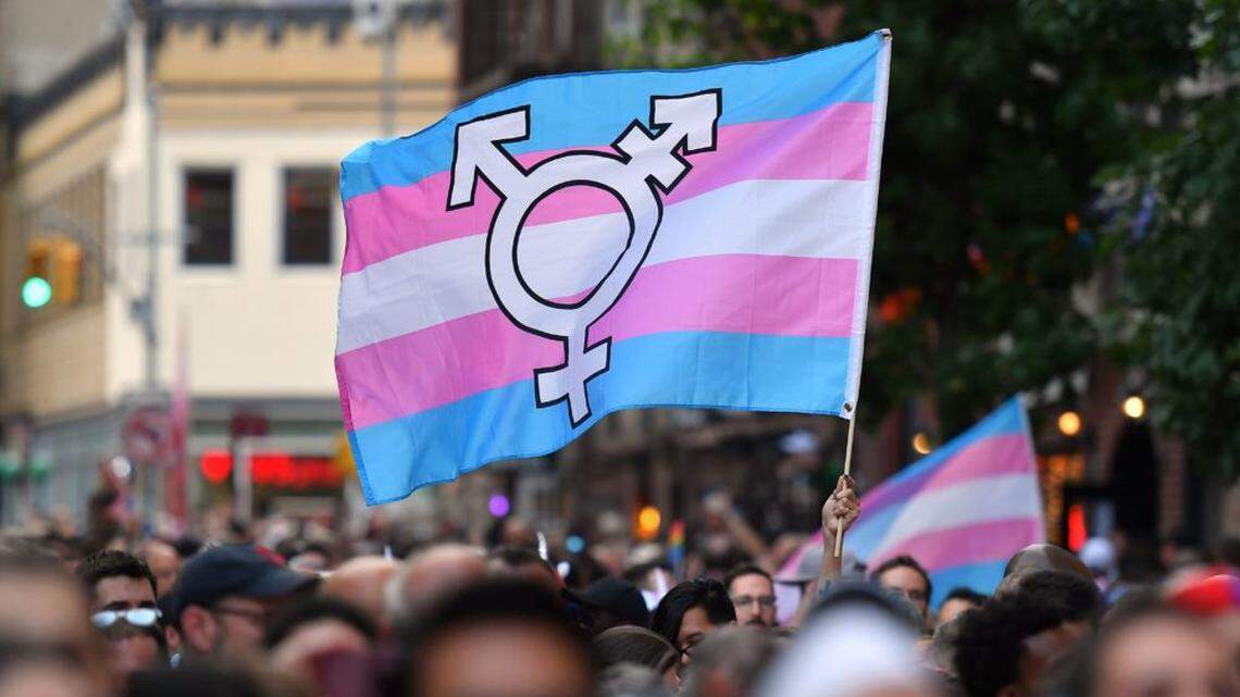 In 2019, a person holds a transgender-pride flag as people gather outside the Stonewall Inn in New York to mark the 50th anniversary of the Stonewall Riots, a turning point in the LGBTQ fight for civil rights.