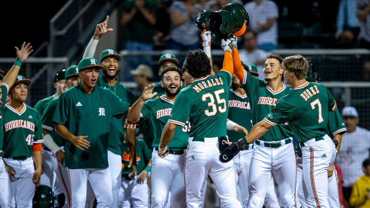 University of Miami batter Yohandy Morales reacts with teammates at home plate after hitting a home run during the fourth inning of an NCAA baseball game against University of Florida inside Alex Rodriguez Park at Mark Light Field in Coral Gables, Florida, on Friday, March 4, 2022.
