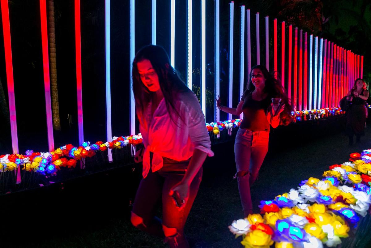 Guests run through a path of illuminated flowers while activating musical notes at NightGarden at Fairchild Tropical Garden. The flowers were previously used as part of a maze at the 2019 version of the NightGarden.