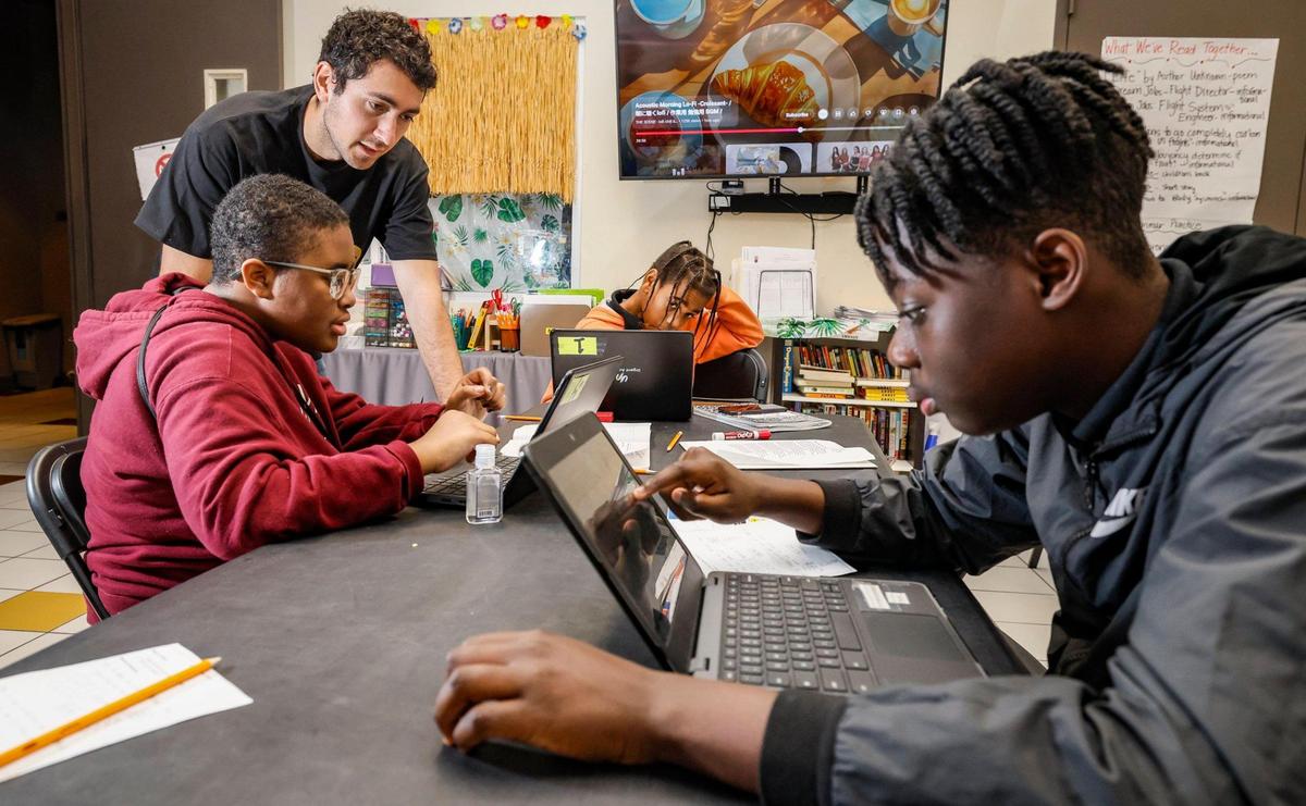 Math teacher, Joey David, at top left, works with, Zahri Kitchen, 12, Javaris Benn, 11, and Payton Rigby, 12, seen seated left to right, during math class at Urgent Academy Middle School in Miami’s Overtown neighborhood.