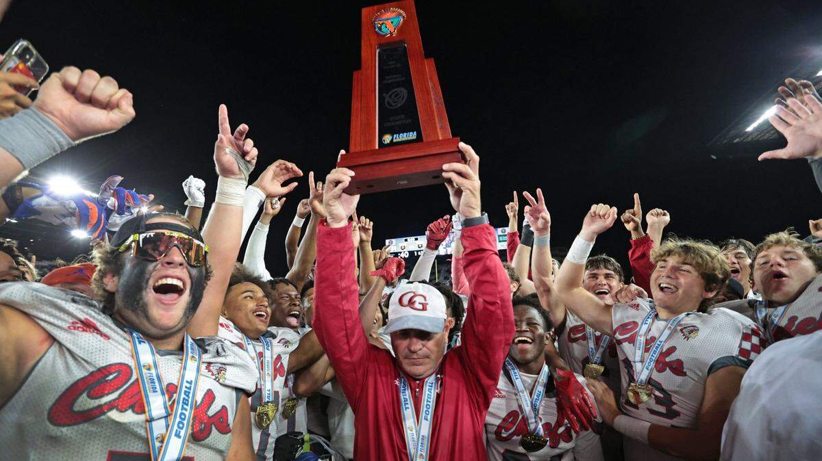 Cardinal Gibbons head coach Matthew Dubuc holds up the Class 4A championship trophy after defeating the Cocoa Tigers at DRV PNK Stadium, in Fort Lauderdale on Thursday, December 16, 2021.
