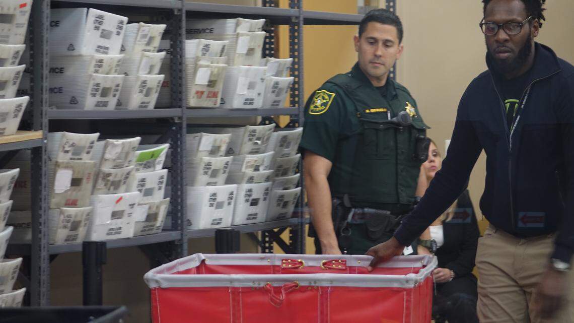 A Broward sheriff’s deputy watches as election workers move sorted ballots Monday, Nov. 12, 2018, at the Broward Supervisor of Elections office in Lauderhill.