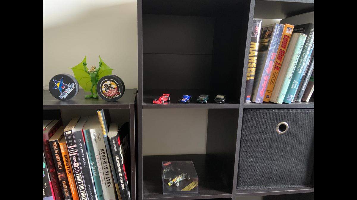 Miami Herald staff writer David J. Neal’s bookshelf, which features hockey pucks, miniature race cars and the novel “The Spook Who Sat by the Door” – showcases his eclectic interests.
