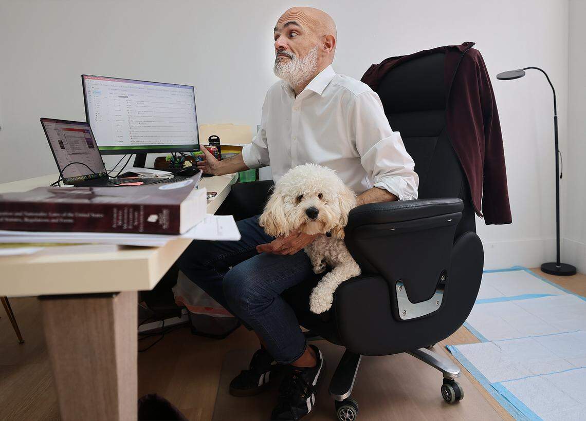 Attorney Victor Martinez works at his desk as he waits with his dog, “Junior,” at his side for the arrival of Rogelio, who was released by ICE. Rogelio, 39, a Guatemalan citizen who has lived in the United States since 2007 and is married to a U.S. citizen, was released by ICE on Wednesday, February 18, 2026, and arrived at his lawyer's office in Miami, Florida.