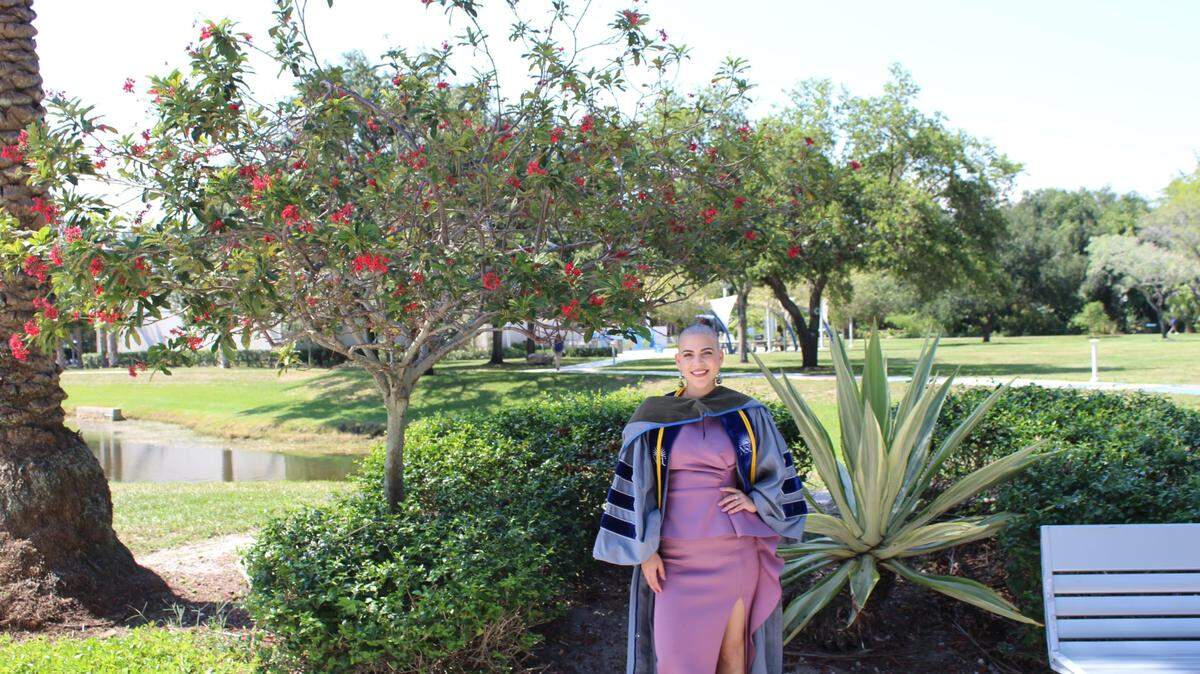 Roxana Chaviano poses for a graduation photo outside Nova Southeastern University in Davie after receiving chemotherapy treatments for breast cancer.
